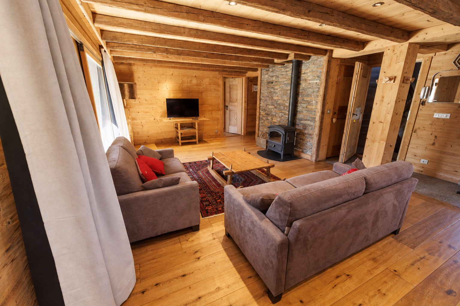 Living room with two sofas, television and wood-burning stove
